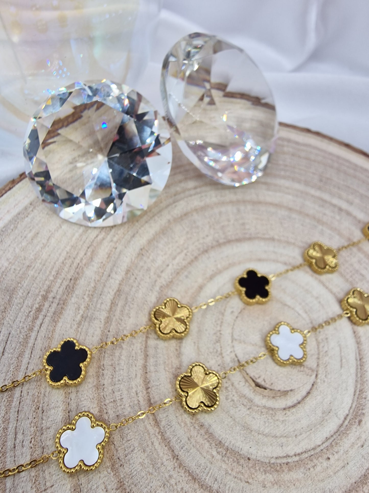 Gold necklace with clover-shaped pendants on a wooden surface